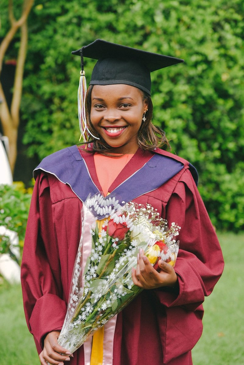 a woman in a graduation gown holding a bouquet of flowers
